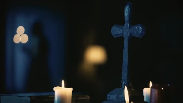 视频记录了一张桌子 上面有神奇的工具 十字架和一本书 女人的身影慢慢地牵着烛台在房间里走来走去 神秘的仪式和仪式 万圣节主题 — 图库视频影像