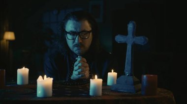 Üzerinde sihirli aletler olan bir masayı çekerken. Bir rahip elinde boncuklarla masada oturuyor, gözleri kapalı dua ediyor. Yaratıcı içerik, Cadılar Bayramı temalı.