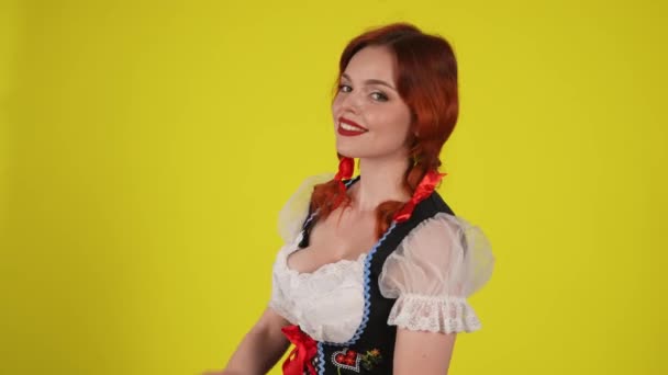 中黄色の背景は 若いドイツ人女性 伝統的な衣装を着たウェイトレスのビデオを隔離し カメラに向かって腕を横切った 10月フェスティバル フェスティバル — ストック動画