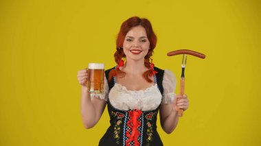Geleneksel bir kostüm giymiş, elinde sosis, bir bardak bira ve gülümseyen genç bir Alman kadının orta sarı arka plan görüntüsü. Ekim Festivali, bira festivali, reklam.