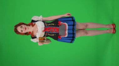 Tam boy, dikey yeşil ekran, genç bir Alman kadını izole edilmiş bir krom anahtar video, garson elinde bir bardak bira, bir tarafı işaret ediyor ve bana bir işaret gösteriyor. Ekim Festivali, reklam.