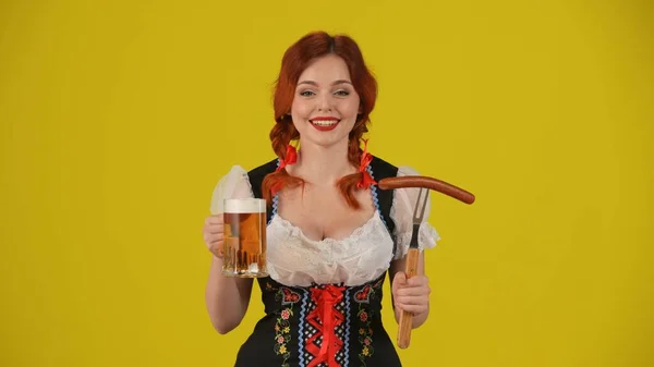 一个年轻的德国女人 穿着传统服装 手里拿着一个啤酒瓶和一杯啤酒 笑着的样子 十月节 啤酒节 — 图库照片