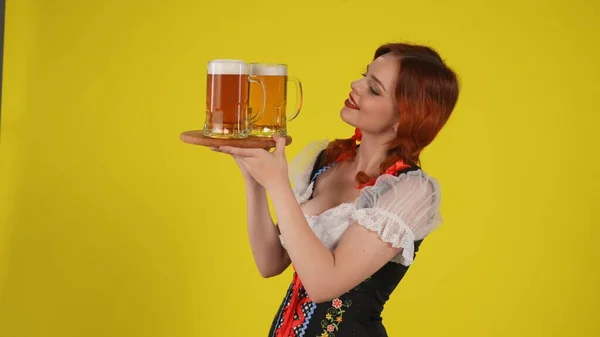 中黄色の背景は 伝統的な衣装を着た若いドイツ人女性の側面ショットを隔離し 3杯のラガー ビールのプレートを保持しました 10月フェスティバル フェスティバル — ストック写真