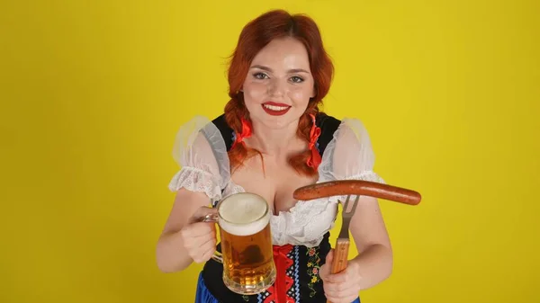 若いドイツ人女性の上から隔離された中黄色の背景は 伝統的な衣装を着て上から撮影したウェイトレスで ガラス ビール ソーセージを提供しています 10月 フェスト — ストック写真