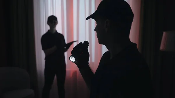 犯罪现场创意的概念 盯着那个手电筒的男人警察男子和妇女站在黑暗的客厅里 环顾四周 拍了一张特写镜头 — 图库照片