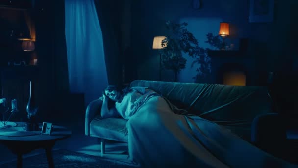 一个年轻女人睡在沙发上的视频 突然灯光闪烁着 她的毯子被某个实体 吹捧着 她跳起来 打电话给某人 吓坏了 — 图库视频影像