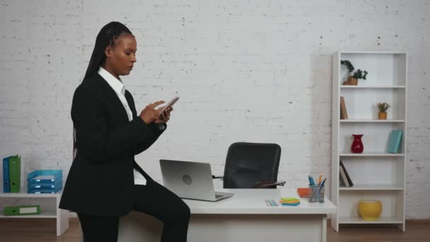 现代女商人的创意概念 办公室里年轻非洲裔美国女性的画像 坐在桌子上拿着智能手机的女人 收到了坏消息 看起来既伤心又不快乐 — 图库视频影像