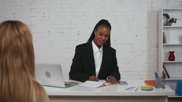現代のビジネスマンコンセプト オフィスの若いアフリカ系アメリカ人女性の肖像画 デスクに座って女性候補者にインタビューする人事部の女性 — ストック動画