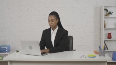 Modern iş kadını yaratıcı konsepti. Ofisteki genç Afro-Amerikan kadın portresi. Dizüstü bilgisayarda çalışan bir kadın, hayal kırıklığına uğramış bir yüz, derin bir nefes al meditasyon yapmaya başla, kameraya gülümse.