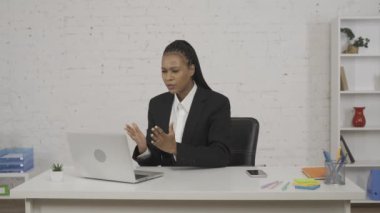 Modern iş kadını konsepti. Ofisteki genç Afro-Amerikan kadın portresi. Dizüstü bilgisayarda çalışan bir kadın, kötü haber almış, üzgün ve çaresiz görünüyor, mutsuz yüz ifadesi. HDR BT2020 HLG