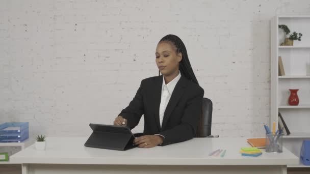 現代のビジネスマンコンセプト オフィスの若いアフリカ系アメリカ人女性の肖像画 机に座ってタブレットで作業している女性は スタイラスで 笑顔に焦点を当てた何かを描いている Hdrについて — ストック動画