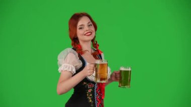 Geleneksel bir kostüm giymiş, elinde iki bardak bira, bir tane sunan ve gülümseyen genç bir Alman kadının krom anahtar videosu. Ekim Festivali, bira festivali.