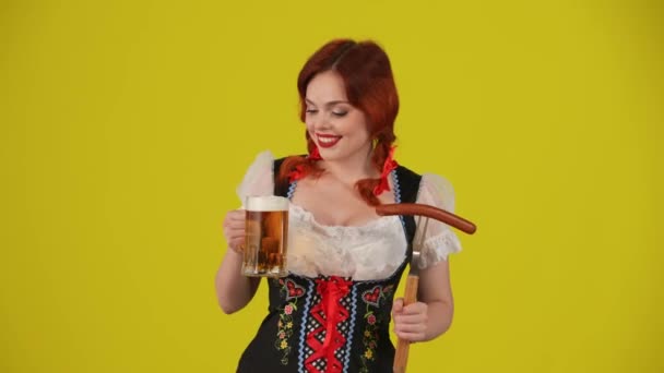 ドイツの若い女性 ウェイトレス 伝統的な衣装を着て ワクワクと興奮を表現するビールを保持する中黄色の背景のビデオ 10月フェスト ビール祭り — ストック動画