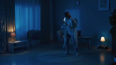 Karanlık bir odada hırsızları, hırsızları, hırsızları arayan genç bir kadının fotoğrafı. Elinde beyzbol sopası ve acil yardım hattını aramak için bir telefon var. Gardiyan ya da güvenlik ajansı, reklam.