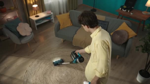 上からのビデオ 幸せな若者はカーペットを掃除し その後掃除機をオフにして カメラを見て微笑みます 広告について — ストック動画
