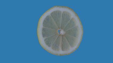 Sağlıklı gıda reklamları yaratıcı konsept. Mavi arka planda izole edilmiş. Meyveler ekrana karşı dönüyor. Yuvarlak limon diliminin yakın plan çekimi tüm açılardan görülebiliyor. Krom anahtar.