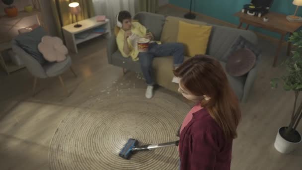 Video Capturing Young Woman Vacuuming Floor Young Man Laying Couch — Stock Video