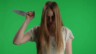 Orta yeşil ekran, ele geçirilmiş bir kadının kroma anahtar görüntüsü, kadın figürü, hayalet, kötü ruh, zombi yetiştirme, bıçak çekme, kameraya bakma. Korku klibi, reklam, yürüyen ölü.