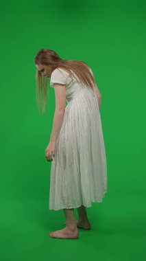 Tam boy dikey yeşil ekran, kadın, kadın figürü, hayalet, kötü ruh, arkadan vurulan zombi görüntüsü. Uğursuz, önsezili bir figür. Korku klibi, reklam, ölü.