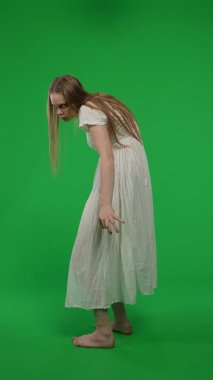 Tam boy yarım ekran dikey yeşil ekran, ele geçirilmiş bir kadın, kadın figürü, hayalet, kötü ruh, yüzünü kameraya çeviren zombi görüntüsü. Korku klibi, reklam, yürüyen ölü..