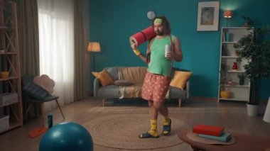 Orta yaşlı bir adam vücudunun üst kısmında ısınmak için spor malzemeleriyle bir odaya girer, fakat tembellik onu alt eder ve birayı seçer. Evde fitness var. Sağlıklı yaşam tarzı kavramı.