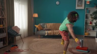Orta yaşlı bir adam ısınmak için spor malzemeleriyle bir odaya girer, fakat tembelliğe yenik düşer ve birayı seçer. Evde fitness var. Sağlıklı yaşam tarzı kavramı.