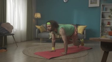 Bir odada motive olmuş orta yaşlı bir adam yorgunluktan bitkin düşene kadar spor paspası üzerinde yerden şınav çekiyor ve sonra da güçsüz bir şekilde yere düşüyor. Evde fitness var. Sağlıklı yaşam tarzı kavramı. HDR