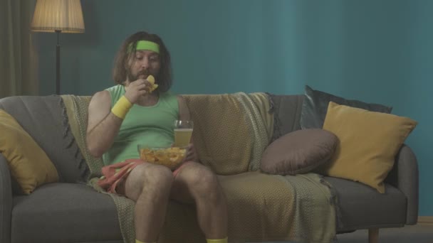 Homem Meia Idade Gordo Senta Sofá Uma Sala Comendo Batatas — Vídeo de Stock