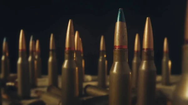 Rows of numerous rifle cartridges on a black background close up. The concept of firearms, shooting range, production and trade of ammunition