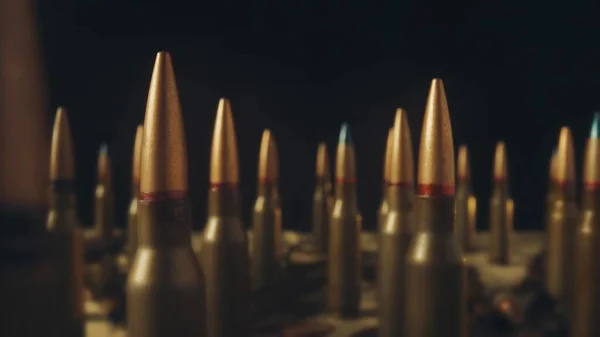 Rows of numerous rifle cartridges on a black background close up. The concept of firearms, shooting range, production and trade of ammunition