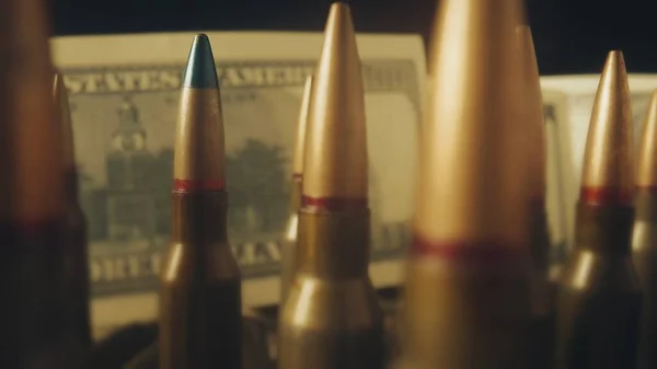 ドル紙幣の背景にあるライフルカートリッジの流れが近づいている 貸し出しの下での武器の販売の概念 武器の助け 軍隊で雇われた仕事 弾薬貿易 — ストック写真