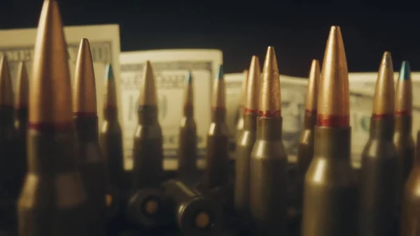 ドル紙幣の背景にあるライフルカートリッジの流れが近づいている 貸し出しの下での武器の販売の概念 武器の助け 軍隊で雇われた仕事 弾薬貿易 — ストック写真