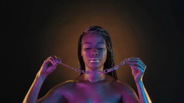 Afroamerikkalainen Nainen Laittaa Kaulaansa Ketjun Jossa Tippoja Nestemäistä Kultaa Vaaleanpunaisessa — kuvapankkivalokuva