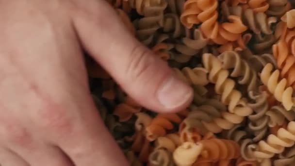 Ujęcie Bliska Męskiej Dłoni Wyciągającej Wiele Kolorowych Spirali Makaronu Zielonego — Wideo stockowe