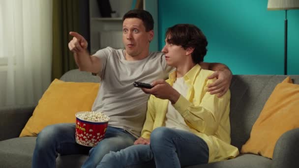 自宅で同性愛者のカップルのビデオ 彼らはソファーに座り テレビを見たり 見るものを選んだり ポップコーンを食べたり 抱き合ったり 話したりしている Lgbt 教育コンテンツ プライド — ストック動画