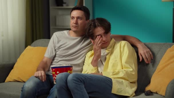 ソファーに座り 一緒にテレビを見たり ポップコーンを食べたりする同性カップルのビデオ 彼らの1人はホラー映画を恐れ パートナーは彼らを慰めようとします Lgbt プライド — ストック動画