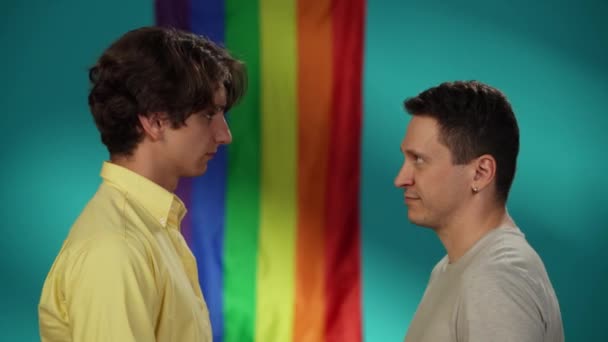 同性愛者の男性カップルのビデオはお互いの前に立って お互いに額を傾けています 背景にレインボーフラッグ Lgbt 教育コンテンツ プライド — ストック動画