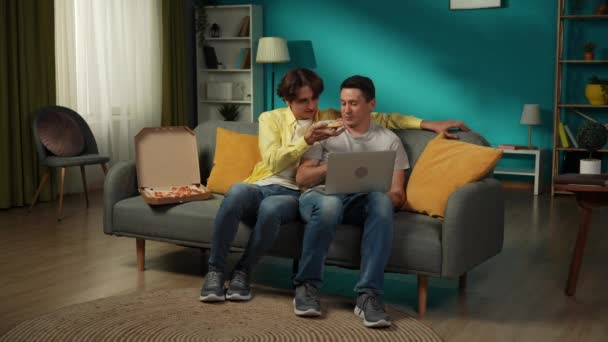 自宅で同性愛カップルのフルサイズのビデオ 彼らはソファーに座り ラップトップで写真を見たり ピザを食べたり 抱擁したり お互いに暖かく話したりしている Lgbt プライド — ストック動画