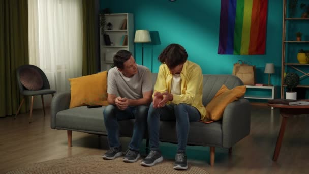 ソファーに座っている同性愛カップルのフルサイズのビデオは 彼らのうちの1人が突然何かについてのストレスと不安を表現します パートナーは彼らを慰めようとする Lgbt 教育について — ストック動画