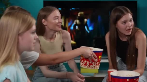 一群青少年 年轻人 女朋友坐在沙发上看电视 恐怖片 系列片 他们在吃爆米花 开玩笑 青少年 青年内容 — 图库视频影像