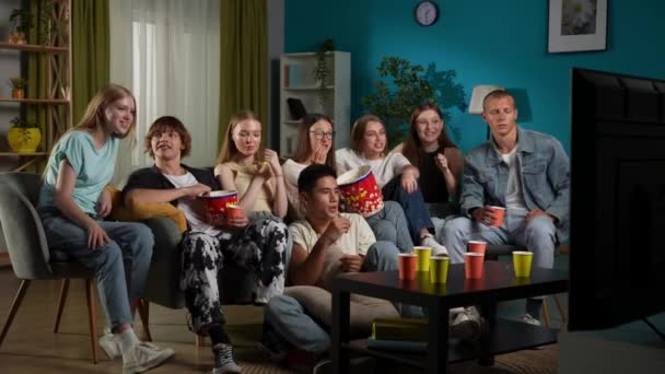 一群青少年 年轻人 坐在沙发上看电视的朋友 恐怖片 系列片 他们在吃爆米花 放声大哭 全尺寸 — 图库视频影像