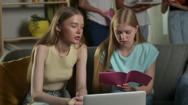 10代の若者 試験の準備 話し合い ノートを見ながらソファーに座っている2人の少女のメディアビデオ — ストック動画