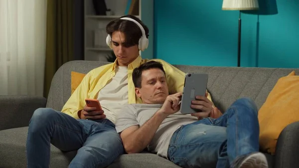 Evde Homoseksüel Bir Çiftin Fotoğrafı Kanepede Yatıyorlar Biri Müzik Dinliyor — Stok fotoğraf
