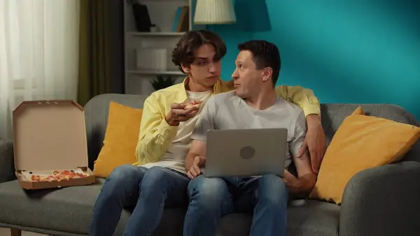 집에서 커플의 그들은 소파에 앉아서 노트북으로 뭔가를 피자를 포옹하고 따뜻하게 — 스톡 사진