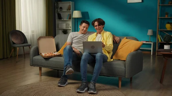 自宅で同性愛カップルのフルサイズショット 彼らはソファーに座り ラップトップで何かを見たり ピザを食べたり 抱擁したり お互いに暖かく話したりしている Lgbt プライド — ストック写真