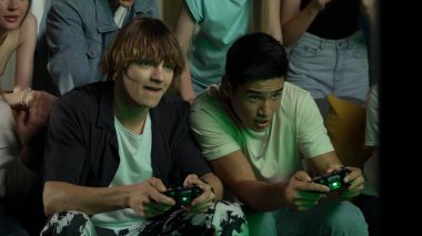 Gençler, gençler, arkadaşlar televizyon başında oturup tezahürat yapıyorlar, iki erkeği cesaretlendiriyorlar, bir konsol, oyun, kavga oynayan çocukları. Oyuncu, genç, gençlik içeriği.