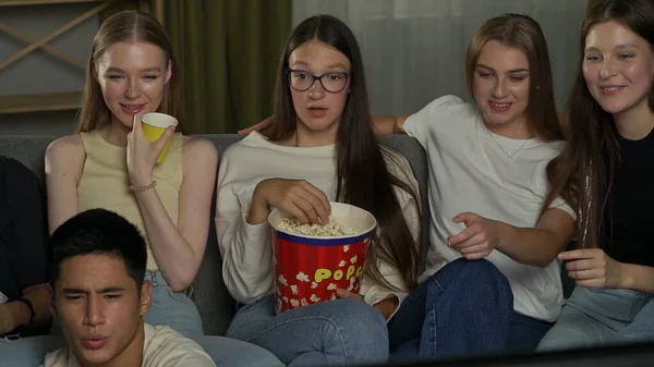 一群青少年 年轻人 坐在沙发上的朋友 看电视 看电影 他们在吃爆米花 开玩笑 青少年 青年内容 — 图库照片