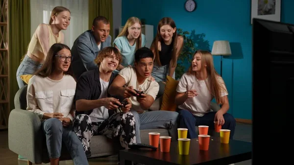 一群青少年 年轻人 朋友们围坐在电视前 站在电视前欢呼 鼓励着两个人 男孩们玩着游戏机 玩游戏 全尺寸 Gamer Teenage — 图库照片
