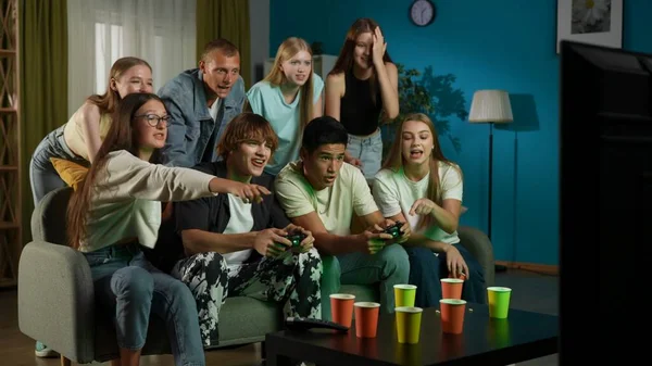 一群青少年 年轻人 朋友们围坐在电视前 站在电视前欢呼 鼓励着两个人 男孩们玩着游戏机 玩游戏 全尺寸 Gamer Teenage — 图库照片