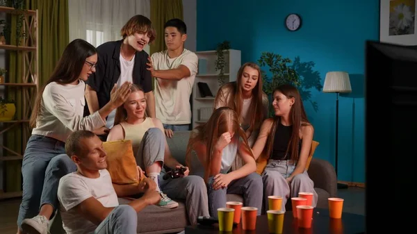 一群青少年 年轻人 朋友们围坐在两个男人身边 男孩们在玩着游戏机 玩游戏 其中之一是在感情上庆祝他的胜利 全尺寸 Gamer Teenage Youth — 图库照片